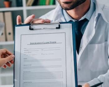 image of doctor showing insurance claim form to patient in clinic